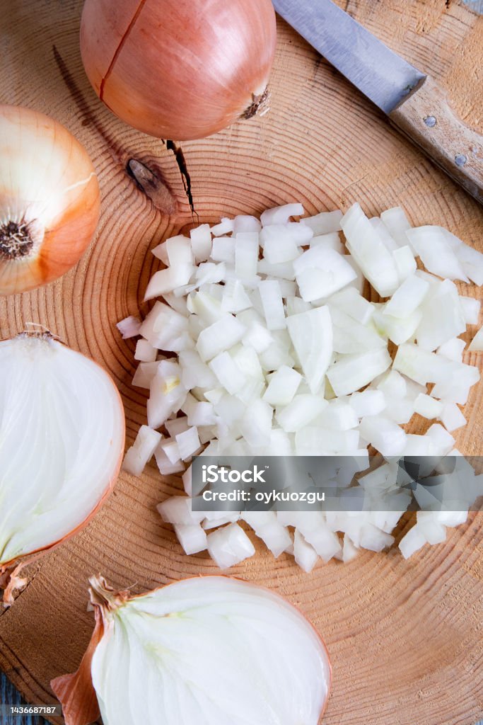 Onions cut in half and chopped on an old wooden board. Top view.