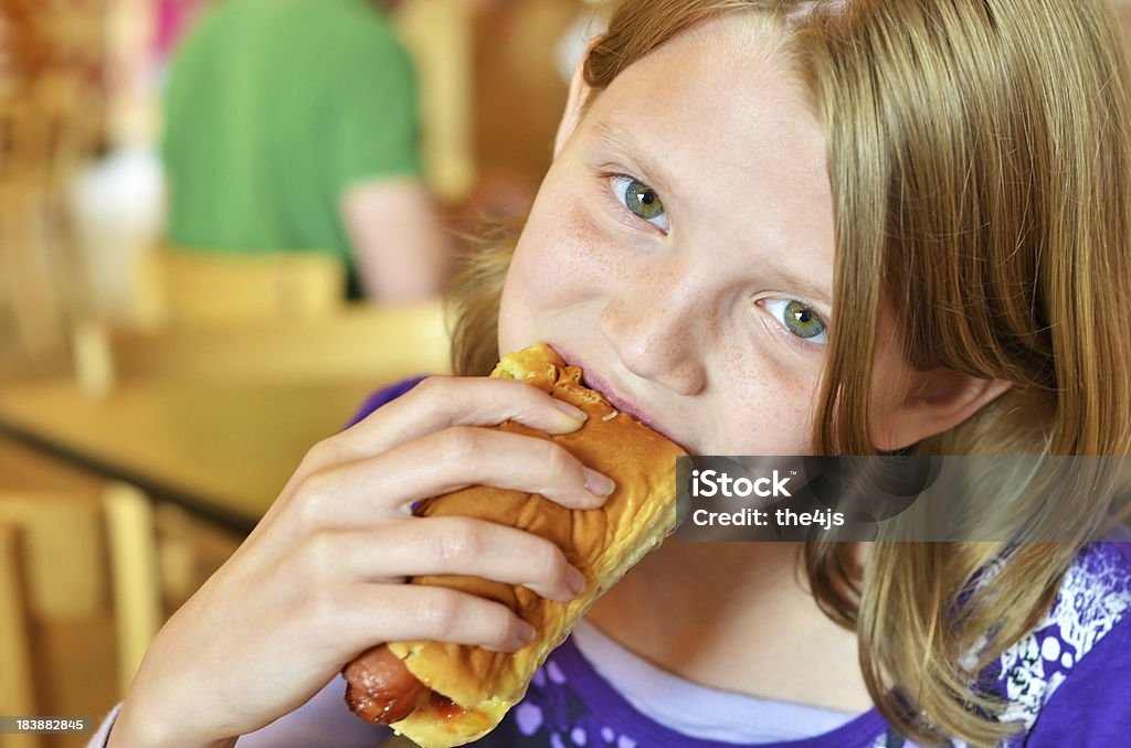 Young girl eating enjoying a hotdog.